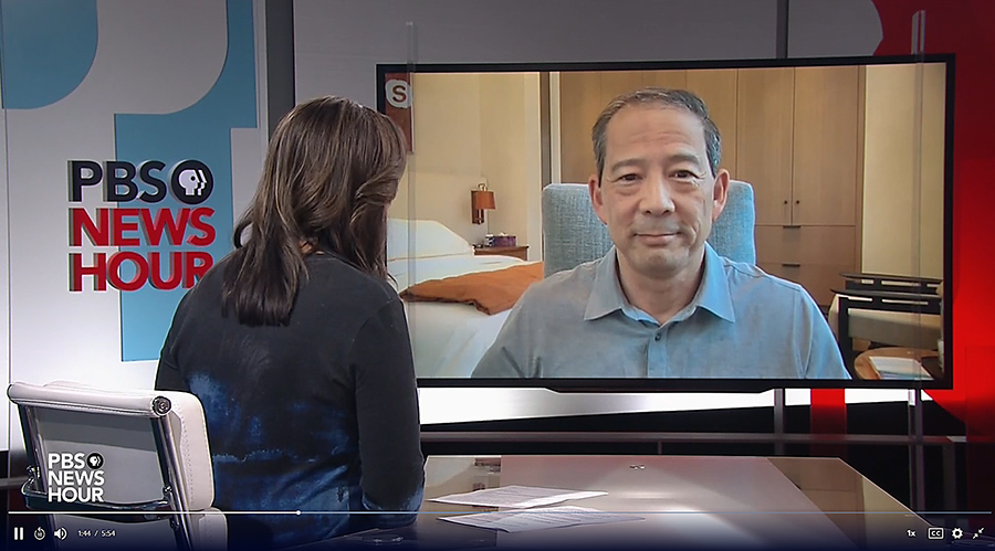 Video still of News Hour studio and anchor Amna Navaz discussing with Norman Chen on a monitor 