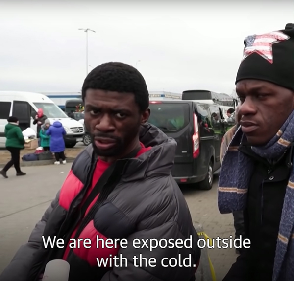 Two African men waiting in the cold to escape Ukraine.
