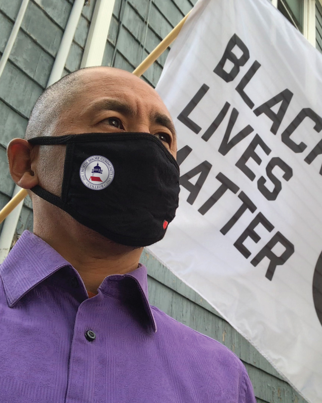 Serious Asian student standing in front of Black Lives Matter flag