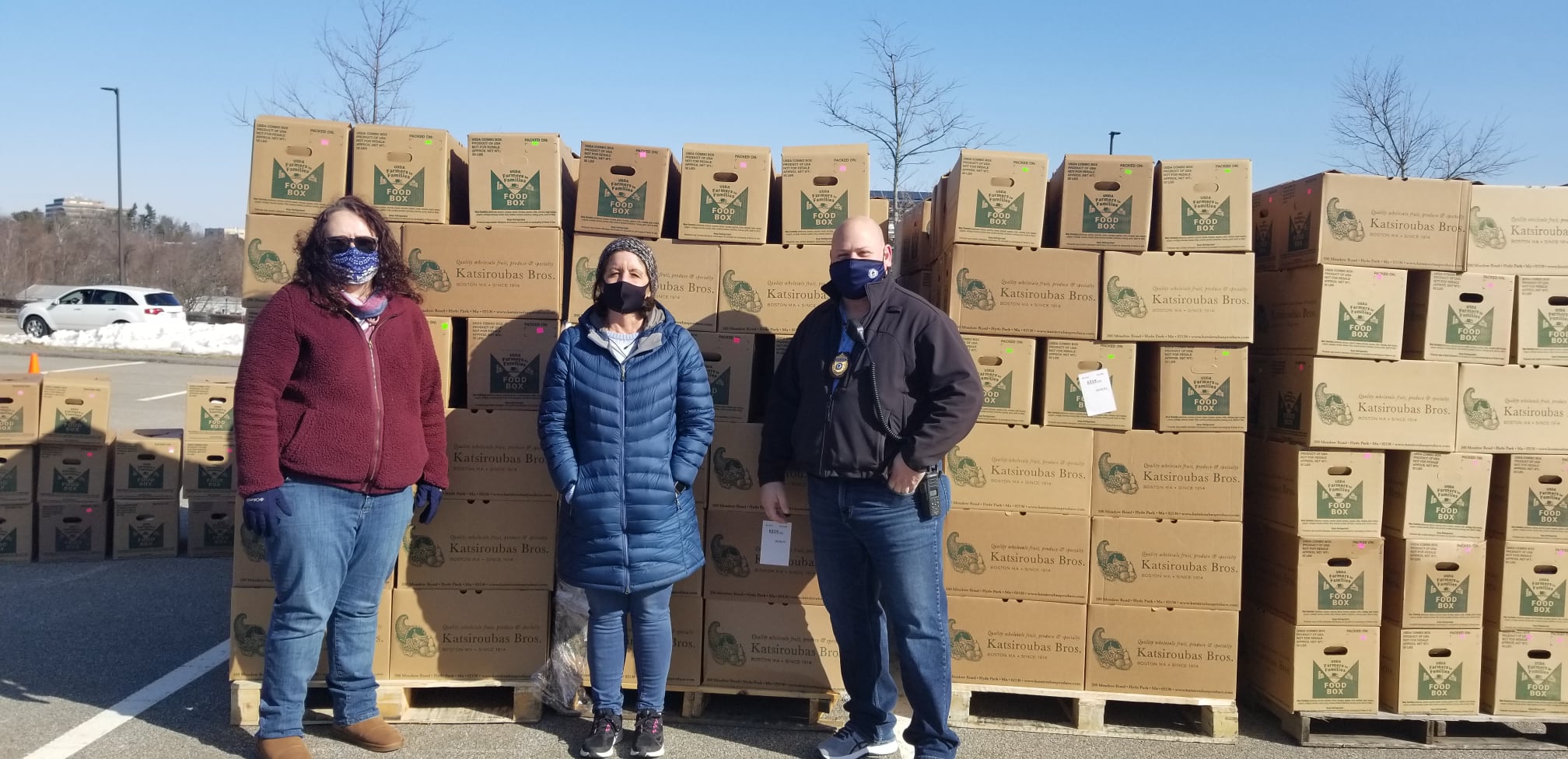 3 people standing in front of stack of food boxes