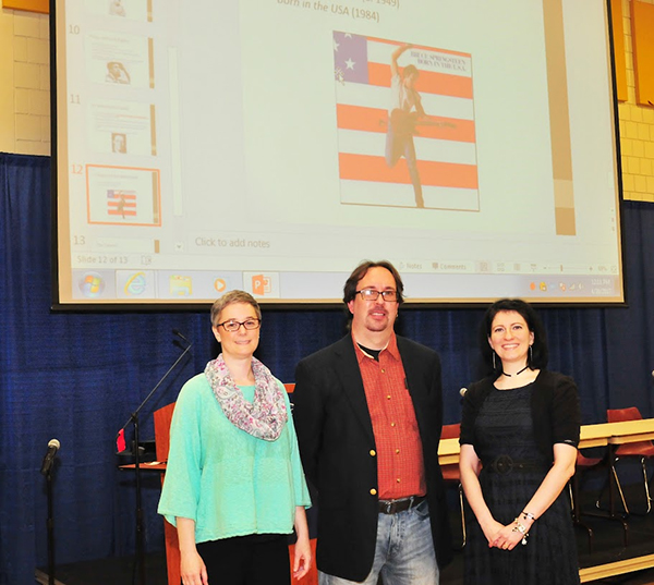 speakers in front of screen with Bruce Springstein album cover