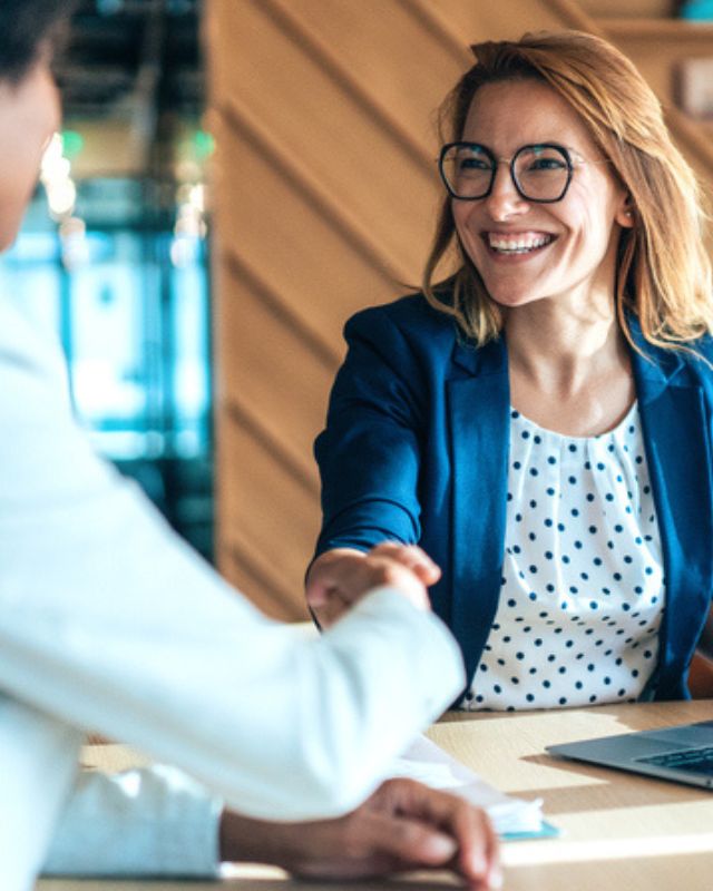 Business women shaking hands over meeting table