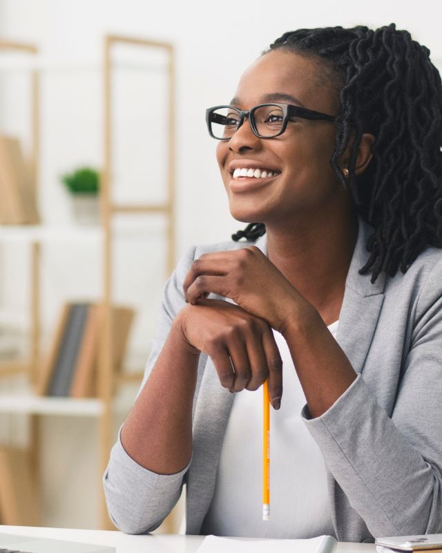 Professional smiling while holding pencil over laptop