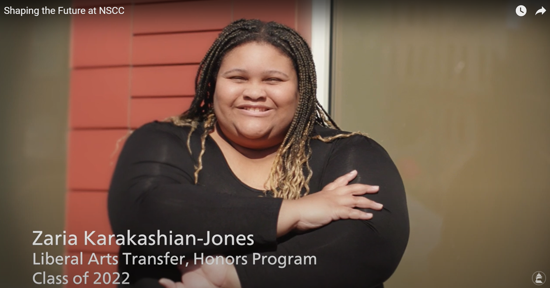 Zaria Karakaashian-Jones in corn rows standing outside in front of red wall