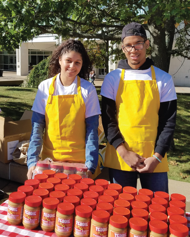 Students behind a table of peanut butter jars to be givine away