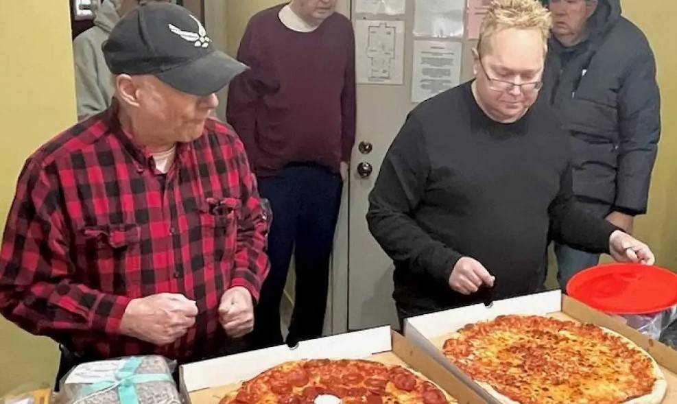 two veterans being served pizza