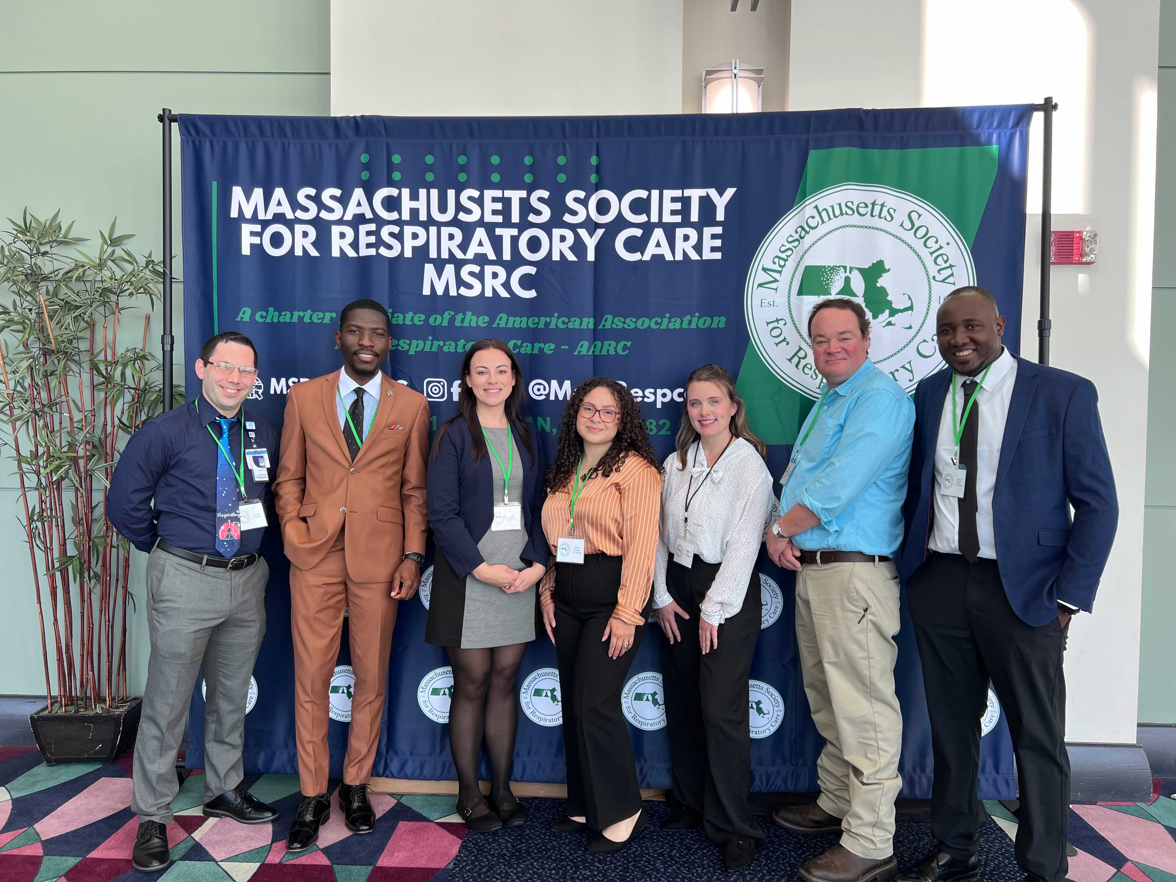 A group of students pose in front of a Massachusetts Society for Respiratory Care banner.