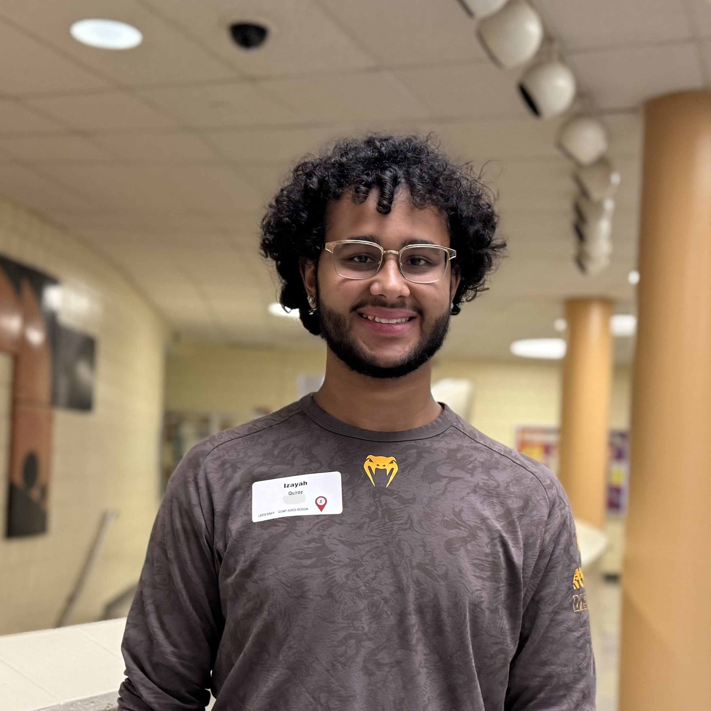 A person in a grey longsleeve shirt smiles at the camera