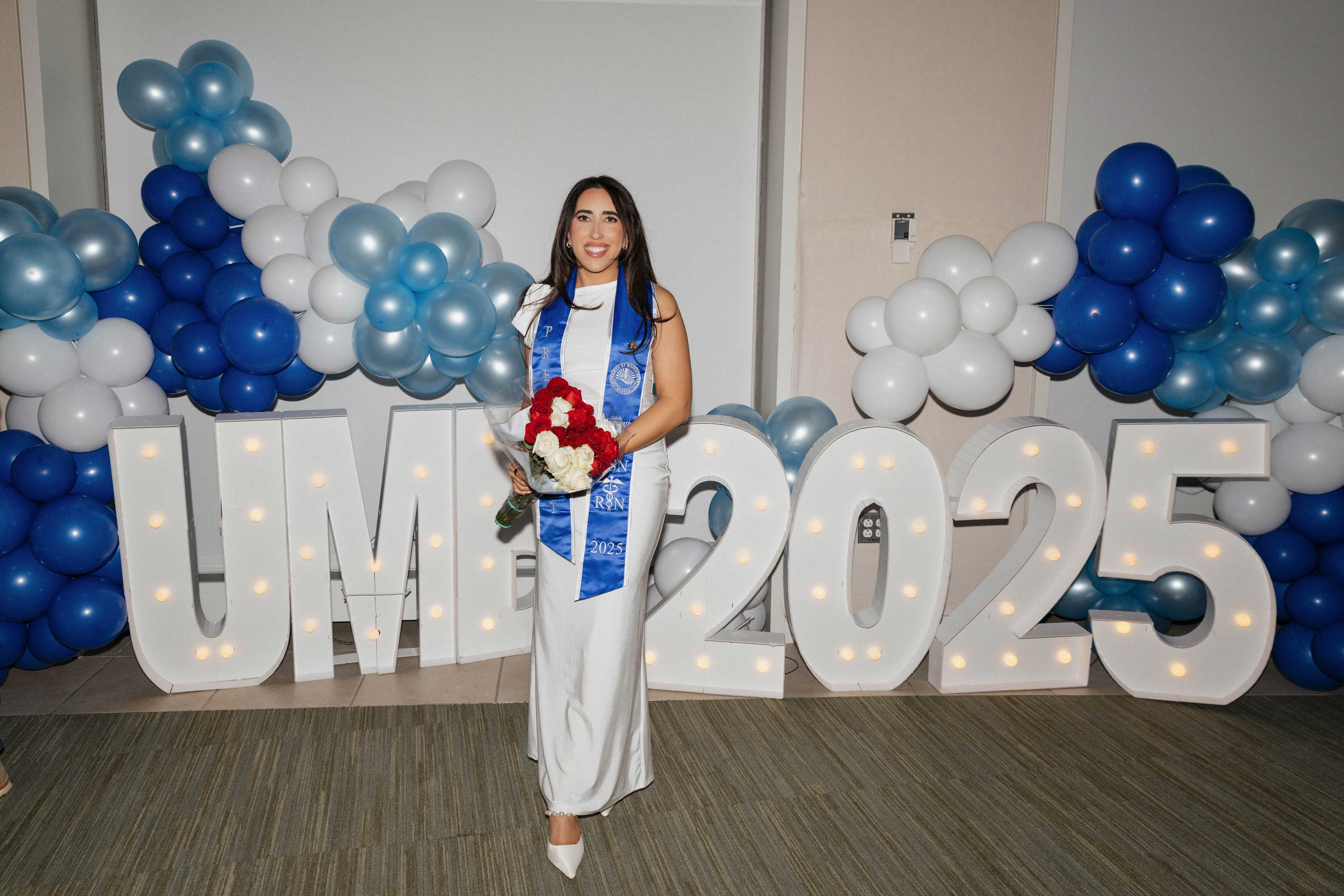 Sam Hartman at UMass Boston graduation Sam Hartman with flowers and a blue stole at UMass Boston graduation