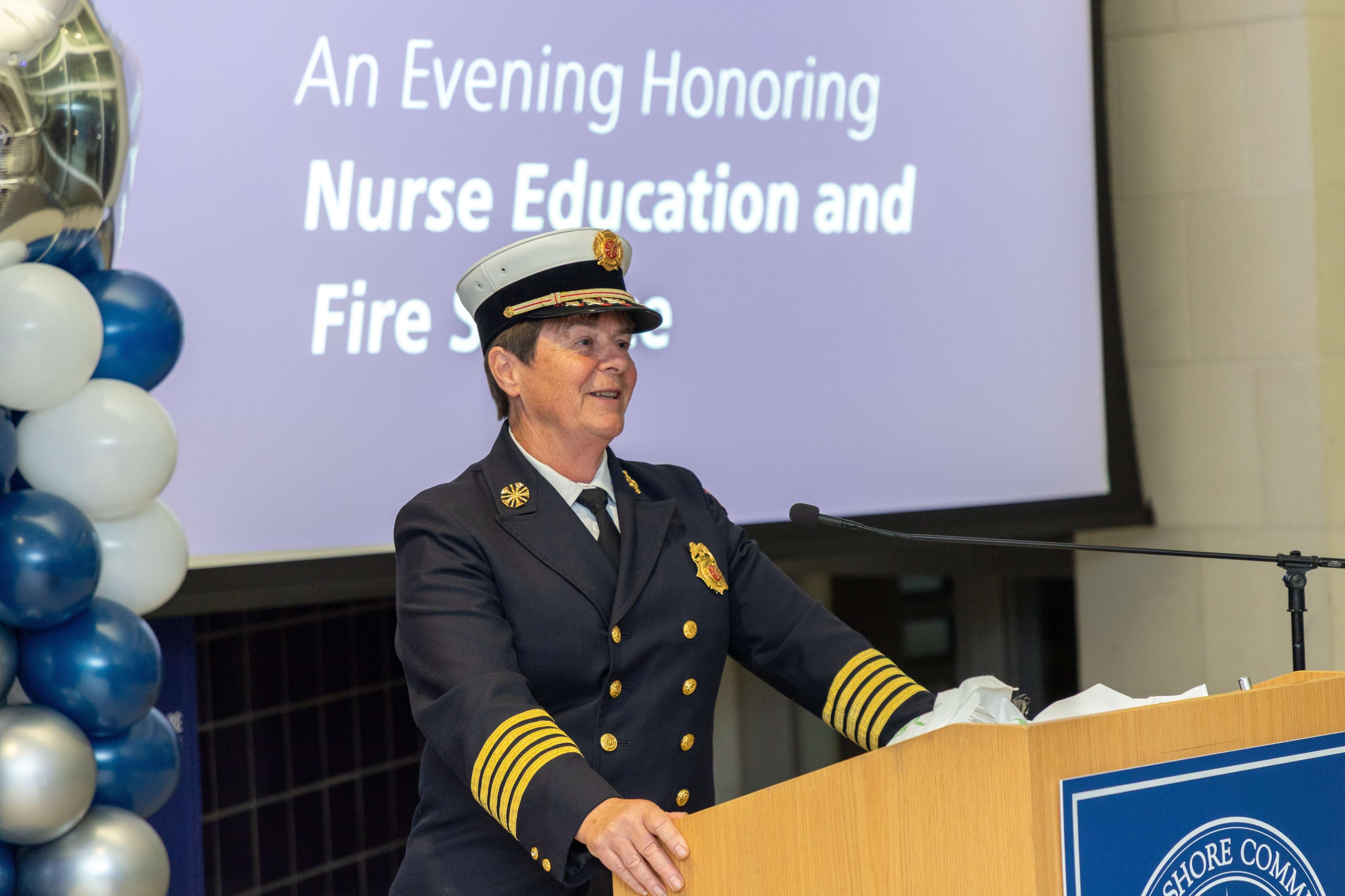 Jen Collins-Brown delivers a speech in uniform at an event honoring the College's Nurse Education and Fire Science programs
