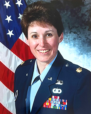 Portrait of Deb Bibeau in USAF uniform in front of US flag.