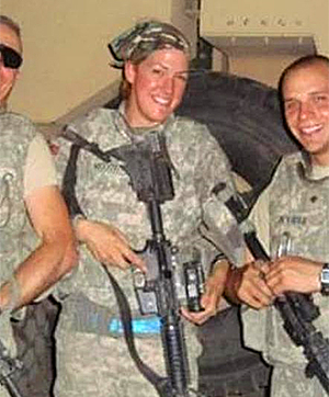 Kim McGowan in camo posing with weapon and two men