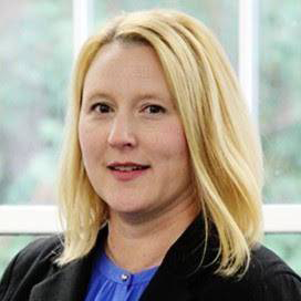 Portrait of Justine in black blazer in front of a window